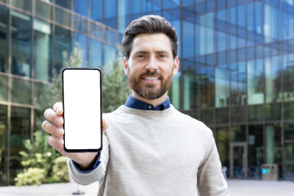 Resident holding a smartphone in front of a modern property building
